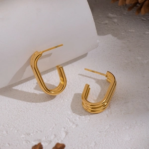 Minimalist 18K gold-plated C-shaped stainless steel earrings on a white stone background
