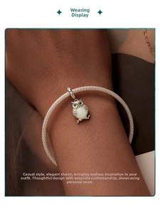 Luminous owl charm on a silver mesh woven bracelet with green gemstone eyes and opal belly