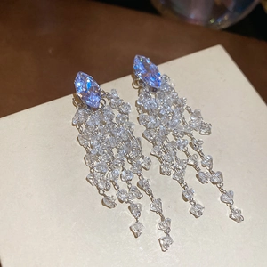 Detailed macro view of diamond-cut purple zircon tassel earrings on beige card display