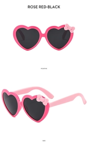 Detail view of heart-shaped kids sunglasses in rose red with bow and black lenses