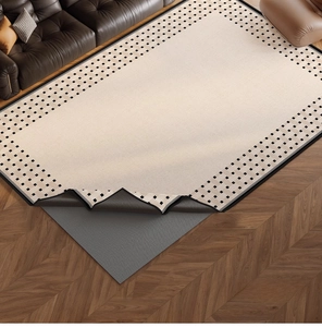 Detail of washable chenille rug showing non-slip backing on dark herringbone wood floor