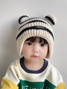 Detail of baby striped knit earflap hat with cute bear ears and DESIGN patch
