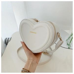 Dettaglio della borsa a tracolla a forma di cuore bianco crema con cerniera dorata