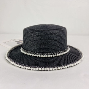 Detail of a vintage black straw boater hat featuring elegant white pearl lace decoration