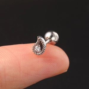 Detailed view of a silver geometric teardrop helix stud with zircon held on a fingertip