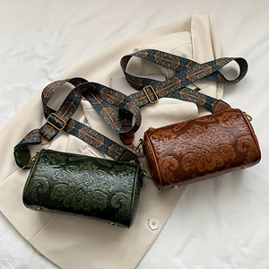 Detail view of vintage embossed leather cylinder bags in dark green and caramel colors