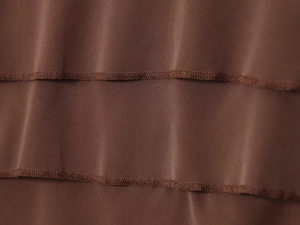 Close-up of deep brown satin fabric layers with ruffled edges and precision stitching