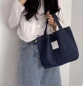 Detail of blue denim lunch bag featuring a cute white bear patch and metal buckle