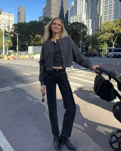Detail shot of a charcoal grey knitted jacket paired with black high-waisted jeans outdoors