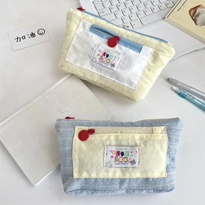 Close-up of cute multi-layer canvas pencil cases with brand label on a desk