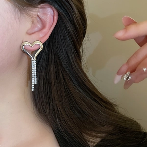 Close-up of model wearing silver heart tassel earrings with sparkling rhinestones