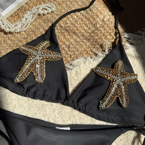 Detail of black bikini set featuring intricate gold and silver rhinestone starfish decor