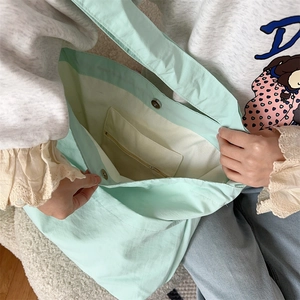 Dettaglio interno borsa tote in tela verde menta con tasca a zip e chiusura magnetica