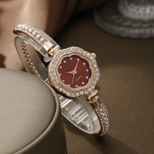 Detail view of burgundy petal dial watch with gold crystal bezel and pearl bracelet strap