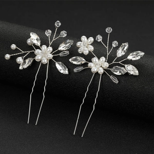 Detailed view of bridal hair pins with white pearls and crystal leaves on black background