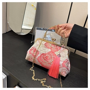 Detail of pink floral embroidery and golden metal handle with tassel on shell bag