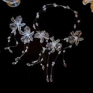 Detailed view of clear floral fringe necklace and earring set on dark background