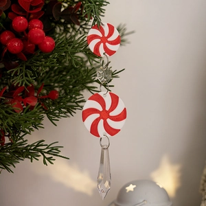 Detail of red and white spiral peppermint ornament with crystal drops on a pine branch