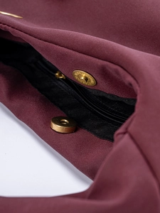 Detail view of burgundy suede bag interior showing golden magnetic snap and zipper pocket