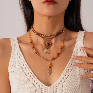 Detail of layered bohemian necklace featuring wooden beads and gold leaf pendants