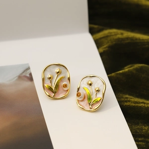 Detailed view of handmade enamel tulip stud earrings on green velvet background