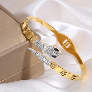 Detailed view of a gold-plated snake bracelet with white crystals on a silk fabric