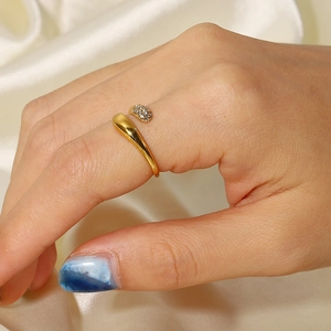 Close-up of gold snake ring with zircon inlay worn over elegant beige silk fabric