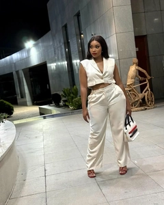 Detalle de chaleco elegante crema y pantalones de pernera ancha en una modelo