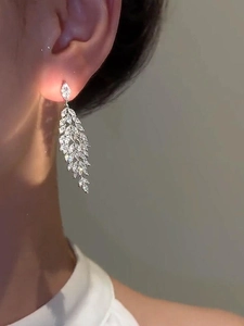 Close-up of silver-plated leaf tassel earrings with sparkling cubic zirconia on a model