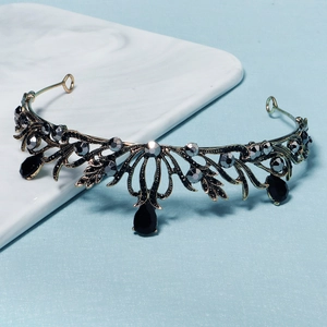 Vintage gold bridal crown with grey crystals and black teardrop gems on marble