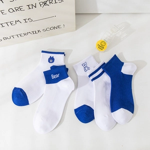 Dettaglio delle calze di cotone blu e bianche con ricamo a orsetto e motivi a righe