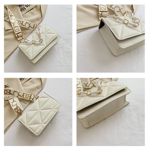 Detail showing white geometric embossed crossbody bag with plastic chain and printed strap