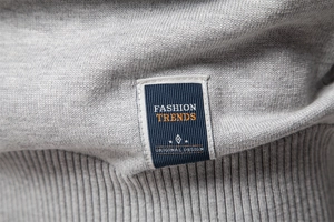 Detailed view of grey knit fabric showing premium label and ribbed hem stitching
