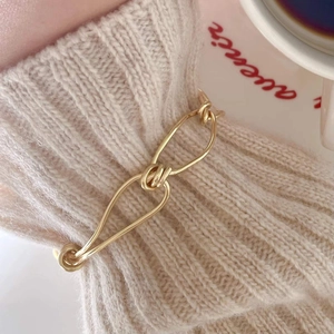 Minimalist 925 sterling silver knot link bracelet shown on a cozy knitted sweater cuff