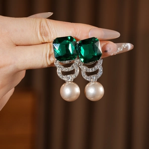 Dettaglio di orecchini vintage con cristalli verde smeraldo e perle a forma di goccia