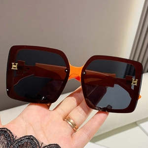 Close-up of rimless butterfly sunglasses with gradient lenses and H-shaped metal hinges