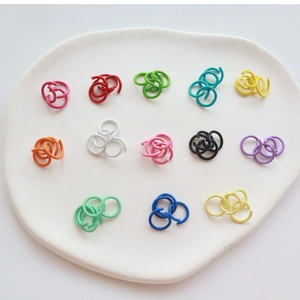 Colorful painted metal jump rings for DIY jewelry making displayed on a ceramic tray