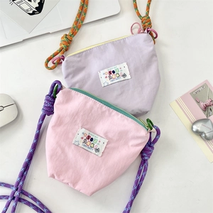 Detail of pink and purple mini crossbody bags with braided straps and top zipper closure