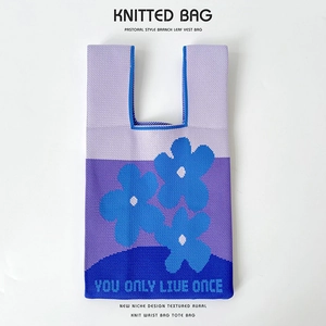 Macro detail of purple knitted bucket bag with blue flower pattern and text embroidery
