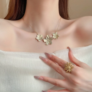Detail of vintage gold flower necklace and ring set with brushed metal texture