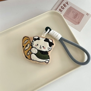 Close-up of plush cartoon cat keychain with embroidery holding a baguette on a tray