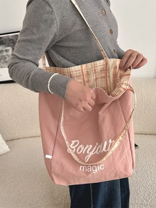 Pink canvas tote bag with Bonjour magic print and checkered lining shown on a beige sofa