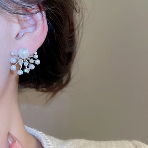 Detail shot of radial pearl earrings with shimmering rhinestones on model's ear