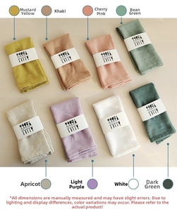 Set of eight folded cotton linen waffle napkins in various colors with paper sleeves