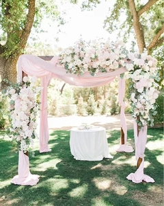 Detail of pink chiffon fabric and floral arrangement with roses on wedding arch