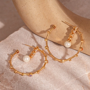Detail of gold-plated hoop earrings with multicolor zircons and a white hanging pearl