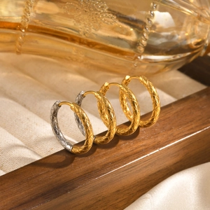 Detailed close-up of gold and silver stainless steel earrings with diamond pattern