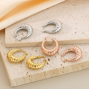 Detailed trio of croissant hoop earrings in gold, rose gold, and silver on stone