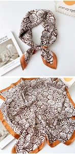 Detail of silk satin scarf with brown rose pattern and orange contrast edges on white