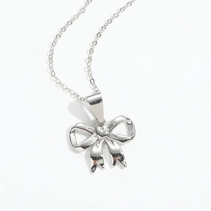 Close-up of elegant silver bow pendant necklace with polished metal texture finish